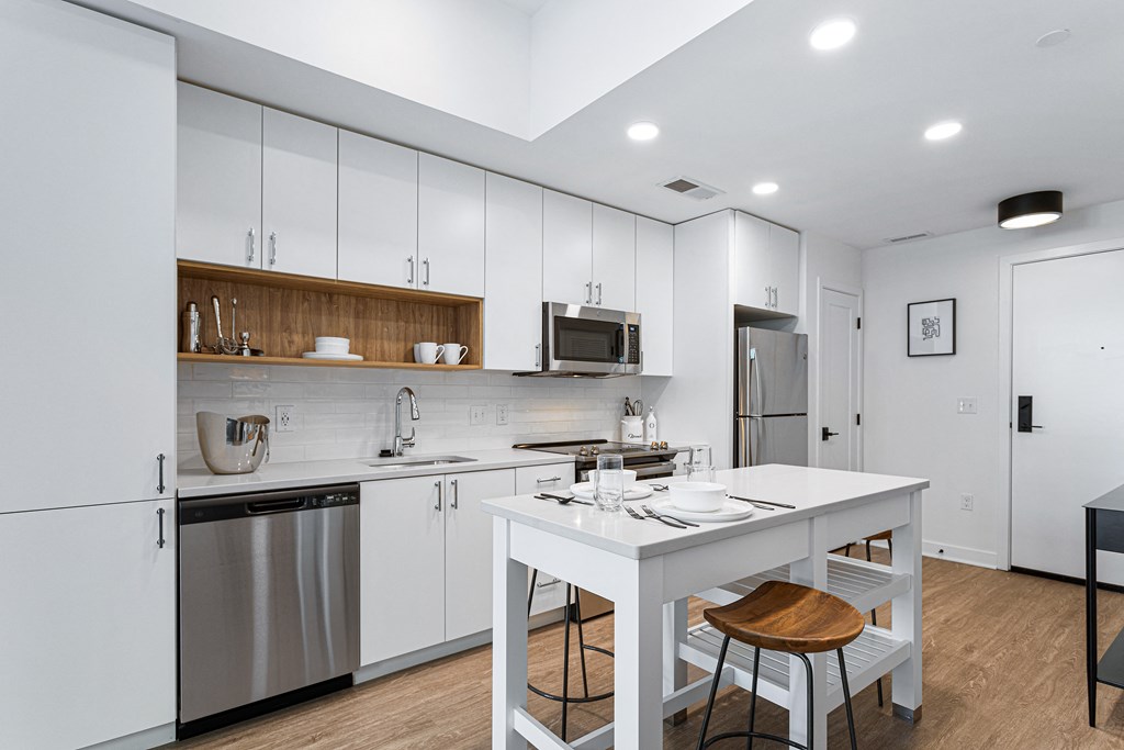 a white kitchen with a white island and stainless steel appliances