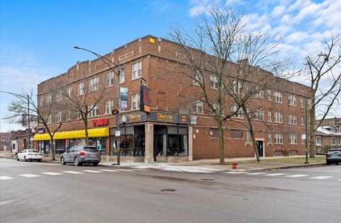 A large brick building with a yellow awning and a sign that reads "Pizza Hut" in front of it.