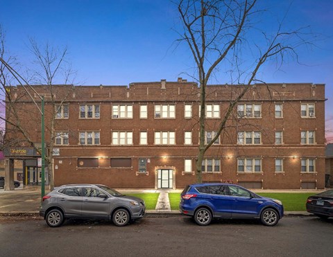 Two cars parked in front of a brick building.