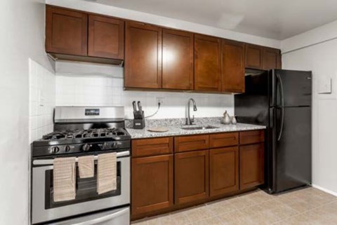 A kitchen with a stove, sink, and refrigerator.
