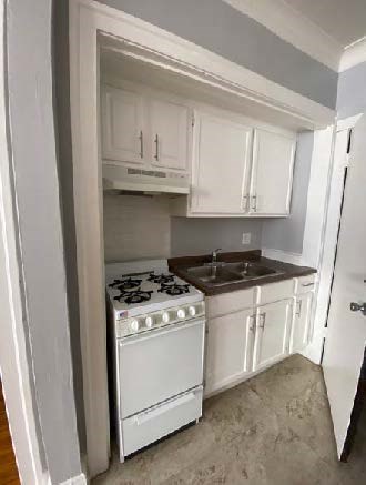 A kitchen with white cabinets and a white stove.