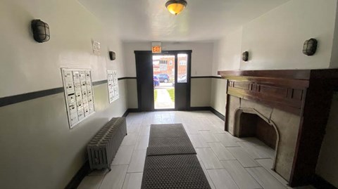 A hallway with a fireplace on the right and a door at the end.
