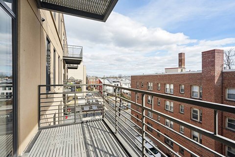 A balcony with a table and chairs overlooks a cityscape.
