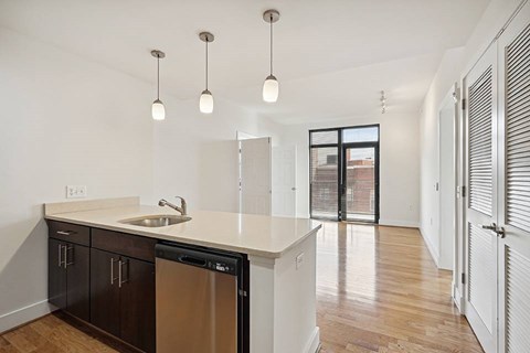 A kitchen with a sink, dishwasher, and cabinets.