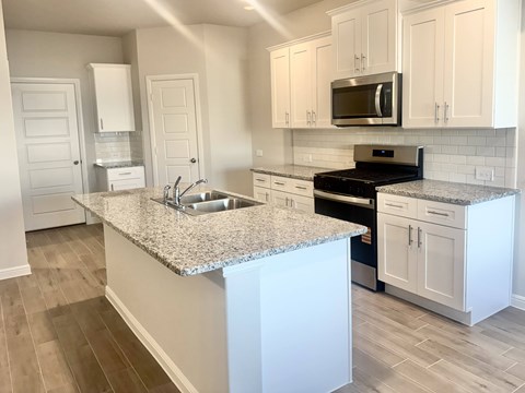 A kitchen with a granite countertop and white cabinets.