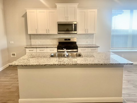 A kitchen with granite countertops and white cabinets.