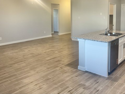 A kitchen with a granite countertop and wooden flooring.