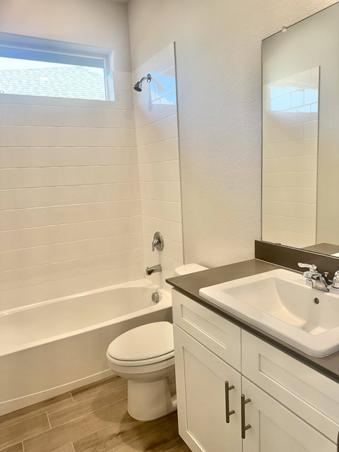 A white toilet sits in a bathroom next to a sink.