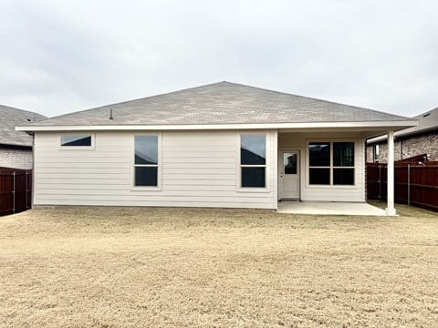A house with a grey roof and white walls with a brown fence in the background.