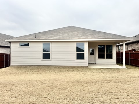 A house with a grey roof and white walls with a brown fence in the background.