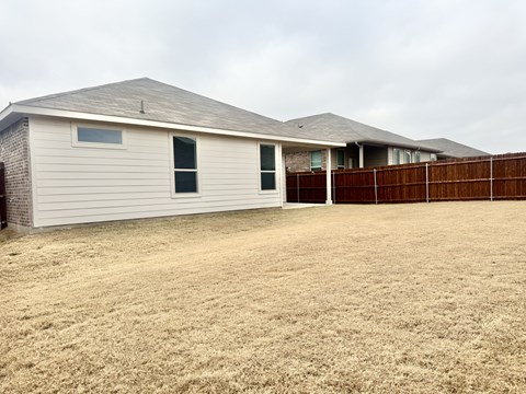 A house with a brown fence and a brown lawn.