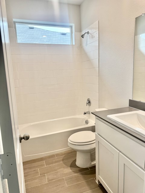 A white toilet sits in a bathroom next to a bathtub.