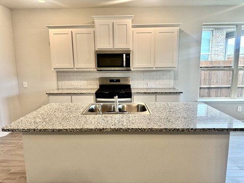 A kitchen with a granite countertop and white cabinets.