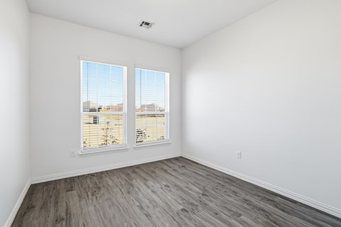 A room with two windows and wooden flooring.