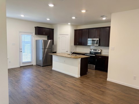 A kitchen with a refrigerator, microwave, and oven.