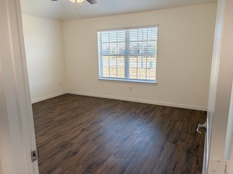 A room with a window and wooden flooring.