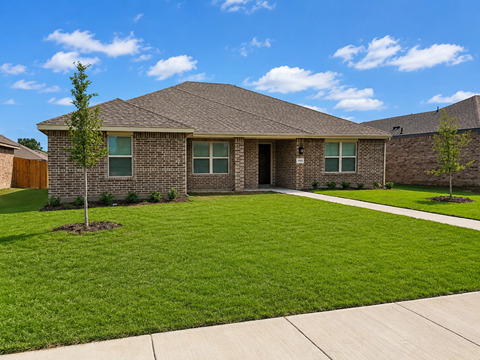 A house with a brown roof and a green lawn.
