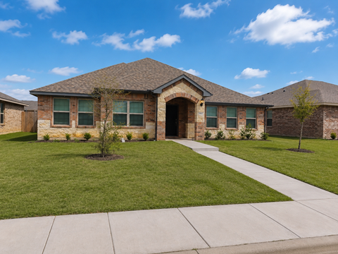 A house with a brown roof and a green lawn in front.