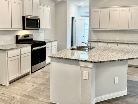 A kitchen with a granite countertop and white cabinets.