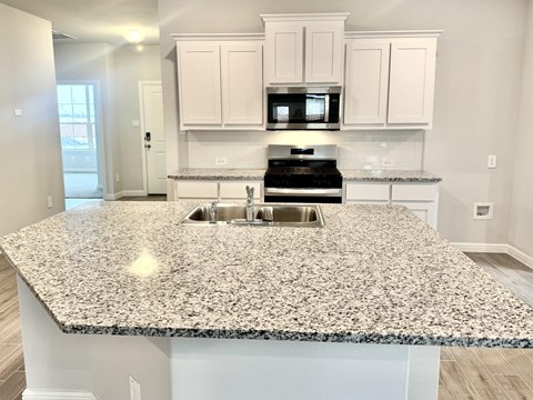 A kitchen with granite countertops and white cabinets.