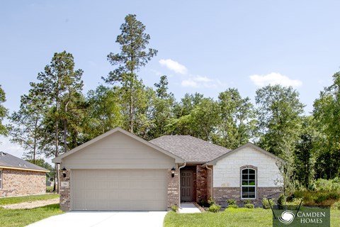A house with a garage is surrounded by trees.