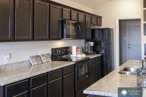 A kitchen with black cabinets and granite countertops.