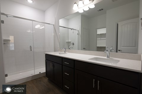 A bathroom with a sink, mirror, and shower.