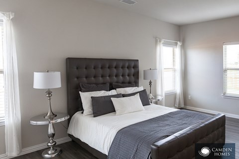 A bedroom with a large bed and a lamp on a side table.