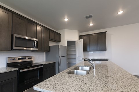 A kitchen with granite countertops and dark wood cabinets.