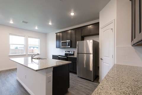 A kitchen with a granite countertop and stainless steel appliances.