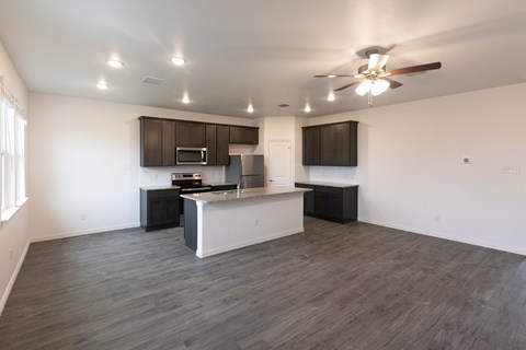 A spacious kitchen with a bar area and a ceiling fan.