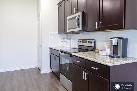A kitchen with dark wood cabinets and stainless steel appliances.
