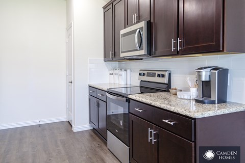 A kitchen with dark brown cabinets and stainless steel appliances.