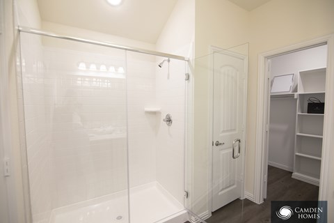 A white bathroom with a walk in shower and a white door.