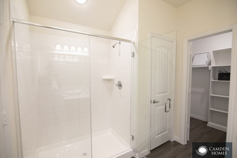 A white bathroom with a walk in shower and a white door.
