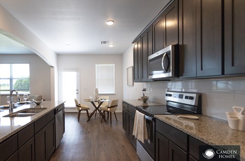 A kitchen with dark wood cabinets and a granite countertop.