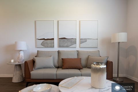 A living room with a grey couch, a white coffee table, and three framed pictures on the wall.