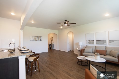A modern kitchen with a bar area and a living room area with a couch.