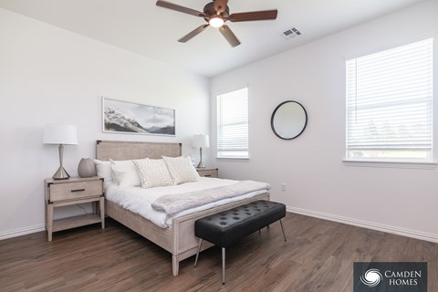 A Camden Homes bedroom with a bed, nightstand, and a ceiling fan.