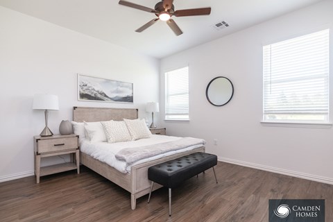A bedroom with a bed, nightstand, and a ceiling fan.