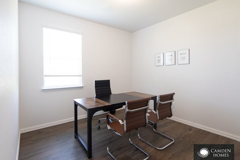 A room with a table and chairs and three pictures on the wall.