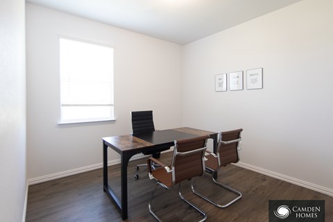 A room with a table and chairs and three pictures on the wall.
