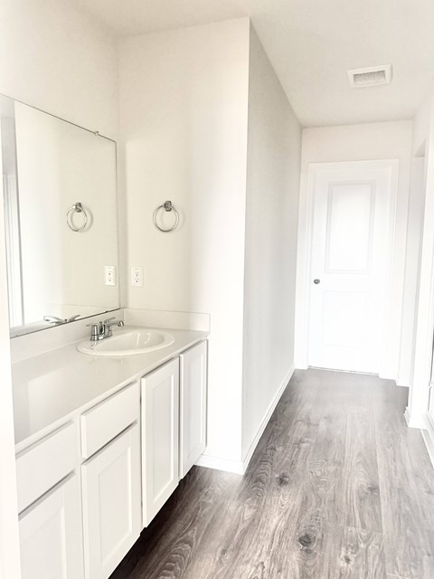A white bathroom with a sink and mirror.