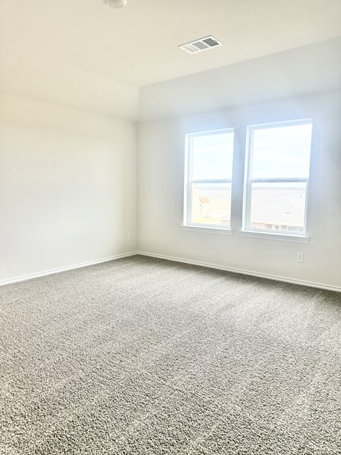 A room with a carpeted floor and two windows.