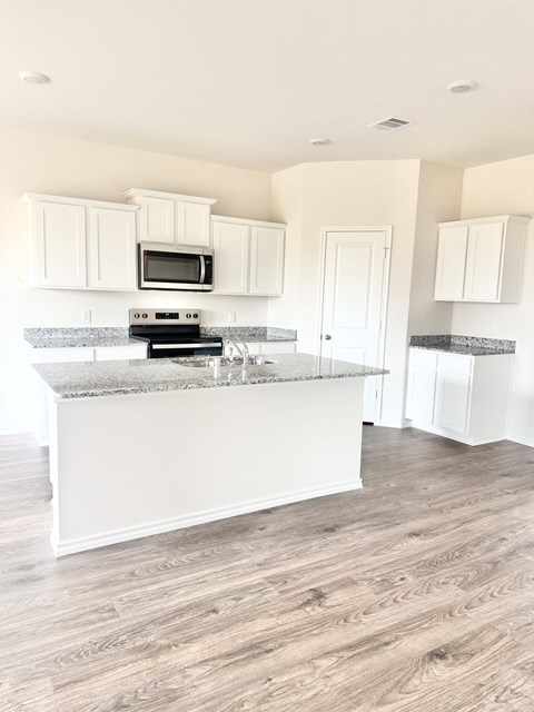 A kitchen with white cabinets and a granite countertop.