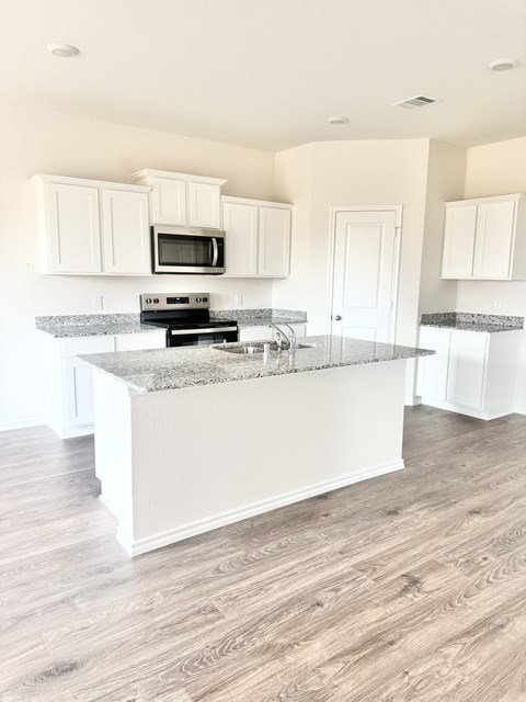 A kitchen with a granite countertop and white cabinets.