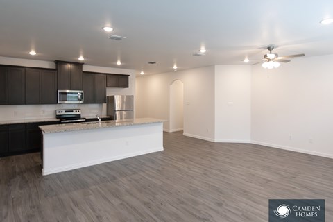 A modern kitchen with a white island and dark brown cabinets.