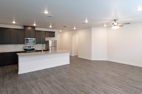 A modern kitchen with a white island and dark brown cabinets.
