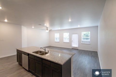 A kitchen with a sink and a countertop in a room with a window.