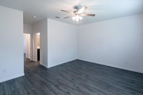 A room with a ceiling fan and grey flooring.
